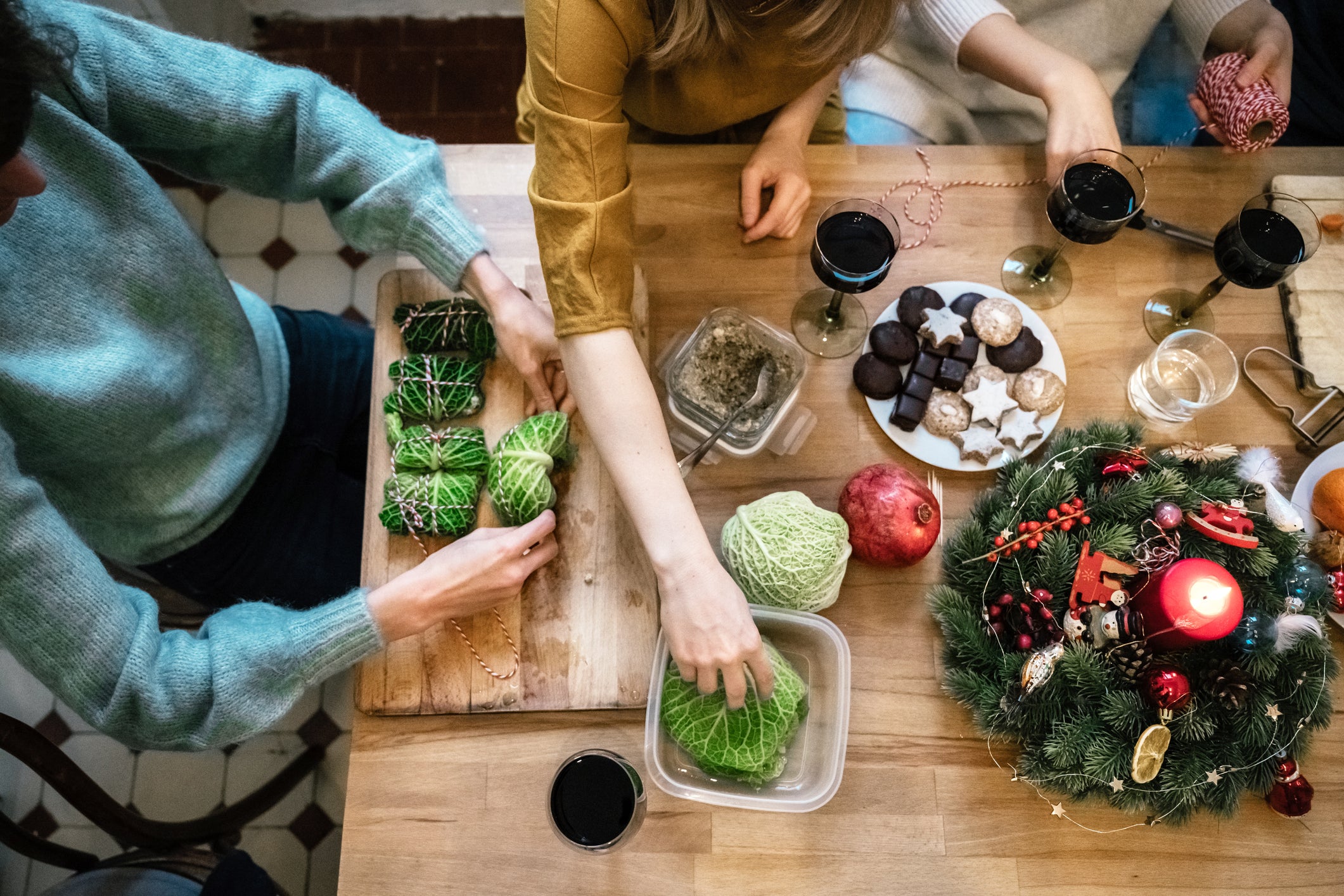 people preparing vegetarian christmas meal together on wooden kitchen table