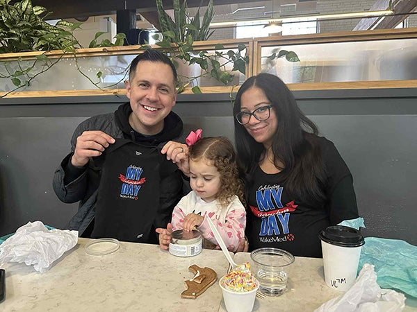 Sarah and husband holding up graduation shirts